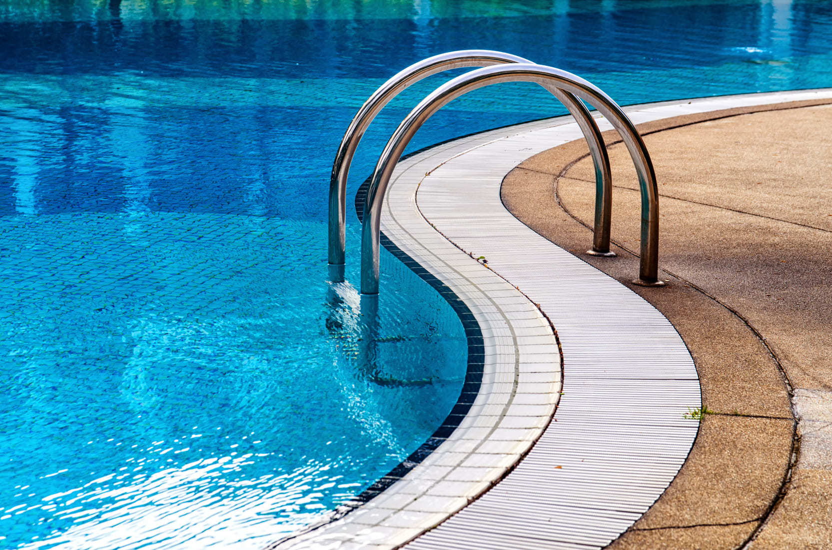 A curved shaped pool with a ladder going into the water